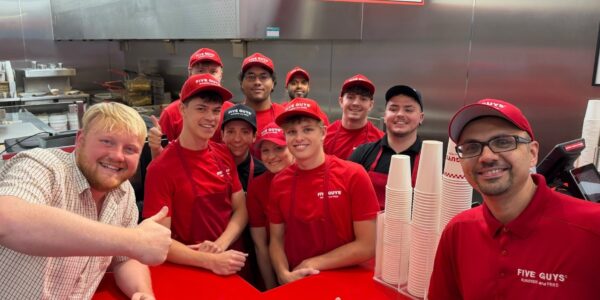 Five Guys employees smiling for a photo with Kaleb Cooper to launch collab with Hawkstone Cider