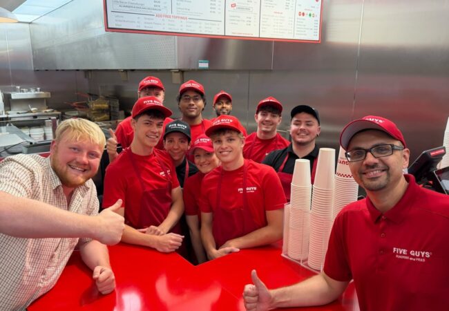 Five Guys employees smiling for a photo with Kaleb Cooper to launch collab with Hawkstone Cider